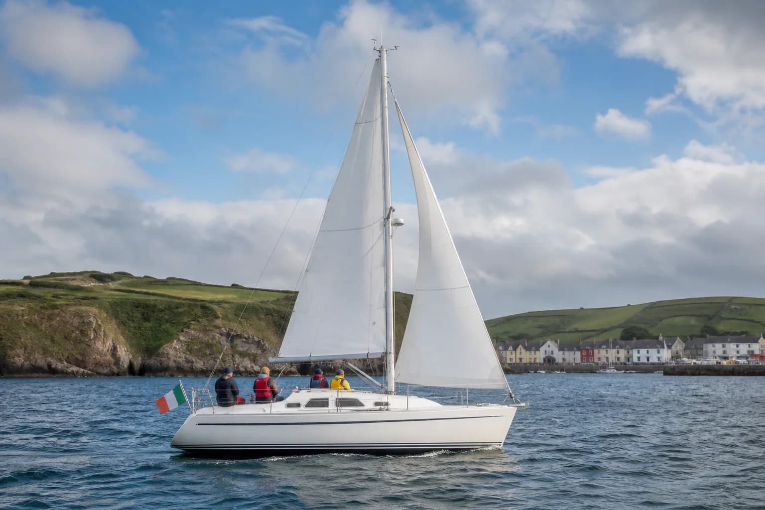 Illustrative Irish coastal sailing scene with a cruising yacht and green harbour headlands.